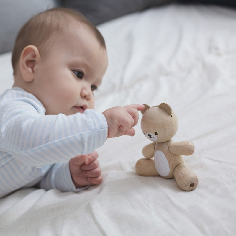 Infant playing with Little Bear from PlanToys
